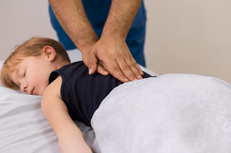 Child receiving gentle chiropractic treatment on a massage table, focusing on back adjustment for improved posture and comfort.