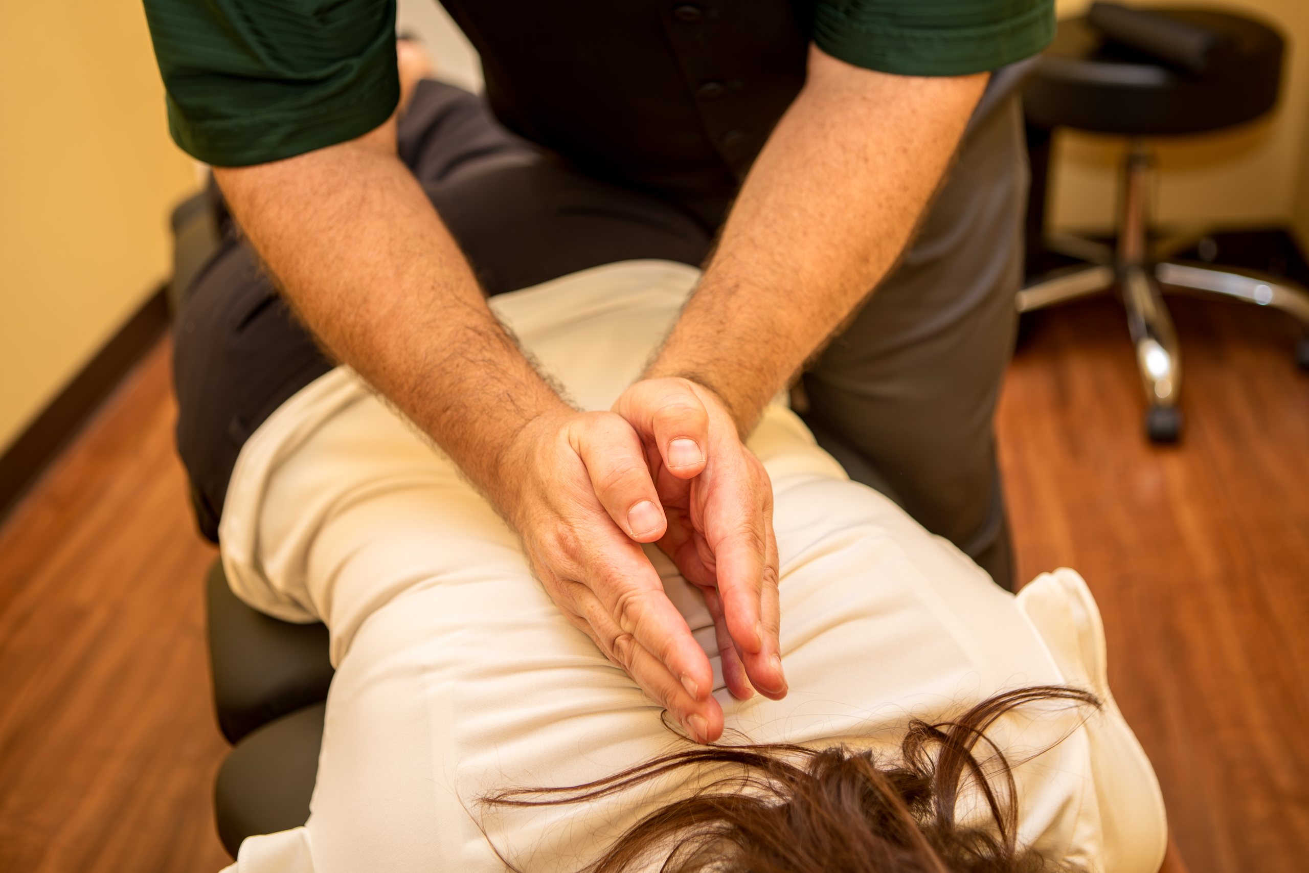 Dr. Michael Cox's hands on a patient's back during a spinal adjustment at Insight Chiropractic in Ormond Beach