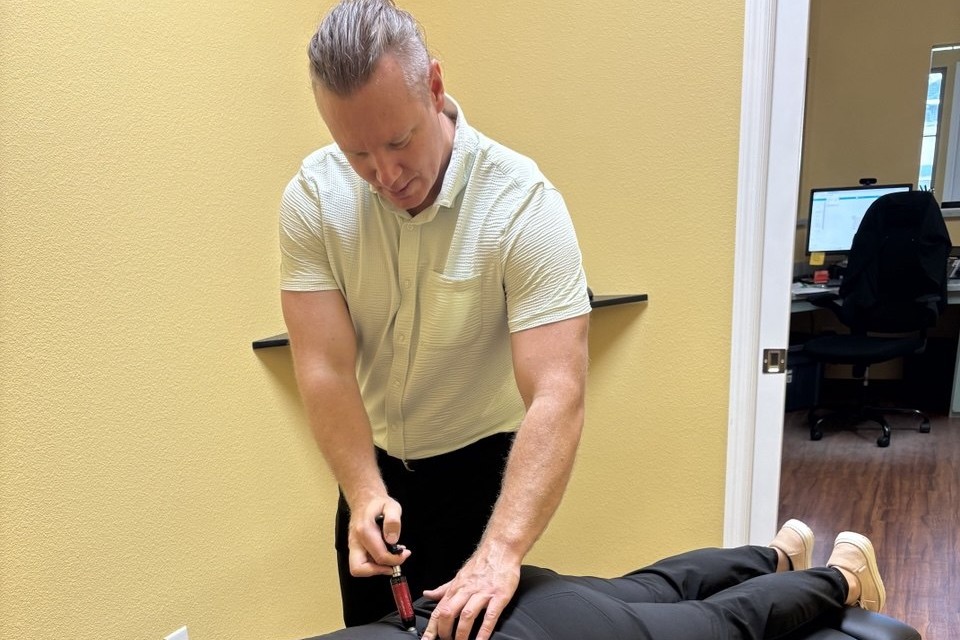 Dr. Christopher Fencl adjusting a patient's low back with a handheld instrument at Insight Chiropractic in Ormond Beach