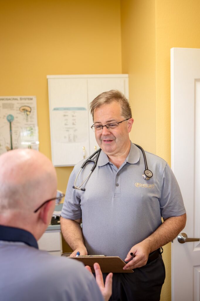Dr. Michael Cox with a stethoscope and clipboard during a physical exam at Insight Chiropractic