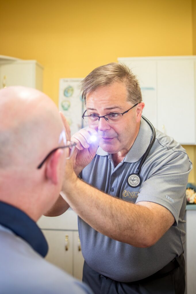 Dr. Michael Cox checking a patient's ear with an otoscope at Insight Chiropractic