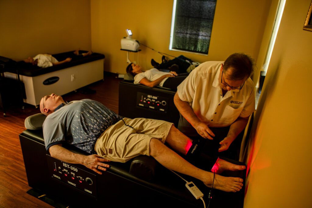 Dr. Michael Cox applying red light therapy to a patient's leg at Insight Chiropractic in Ormond Beach