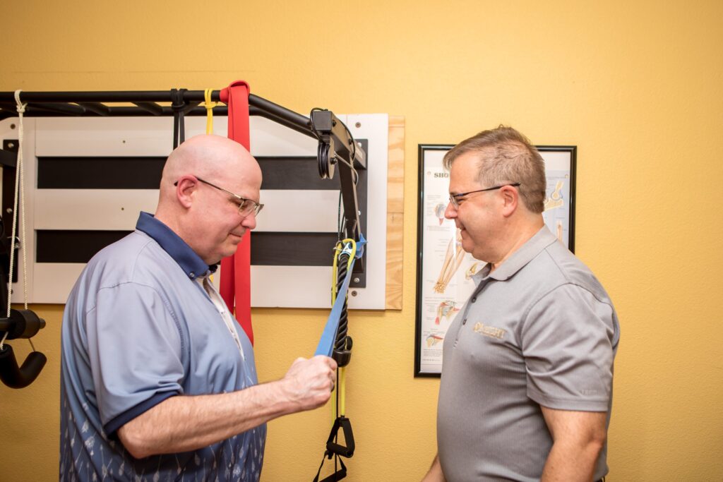 Dr. Michael Cox coaching a patient through a resistance band exercise at Insight Chiropractic in Ormond Beach