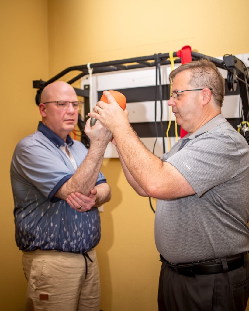 Dr. Michael Cox guiding a patient through a band exercise at the rehabilitation rack at Insight Chiropractic