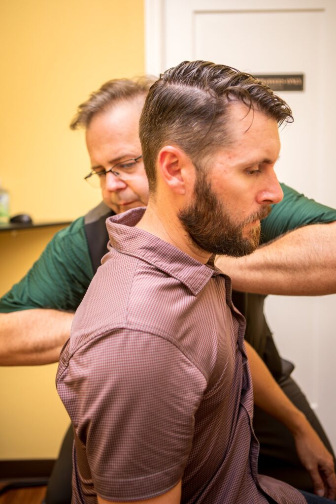 Dr. Michael Cox adjusting a seated patient's neck and shoulder at Insight Chiropractic