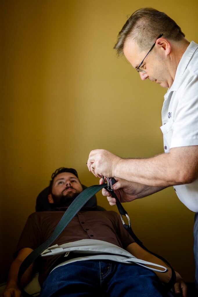 Dr. Michael Cox fitting a patient's harness on the spinal decompression table at Insight Chiropractic